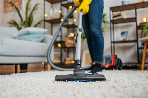 Young Asian woman vacuuming her apartment. Low angle view.